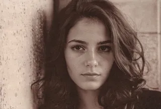 Photo de portrait d'une femme française de 26 ans avec peau naturelle, yeux détaillés, ombres marquées et effet grain de film.