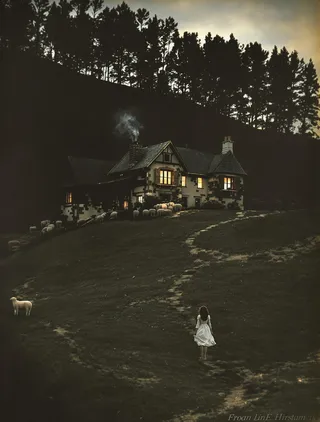 A colorized photograph of an antique cottage sitting on a hillside in the Pyrenees foothills at twilight. Warm light glows through the house windows and smoke rises from the chimney. A young shepherdess in a white dress walks toward the cottage, surrounded by grazing sheep and silhouetted trees behind.